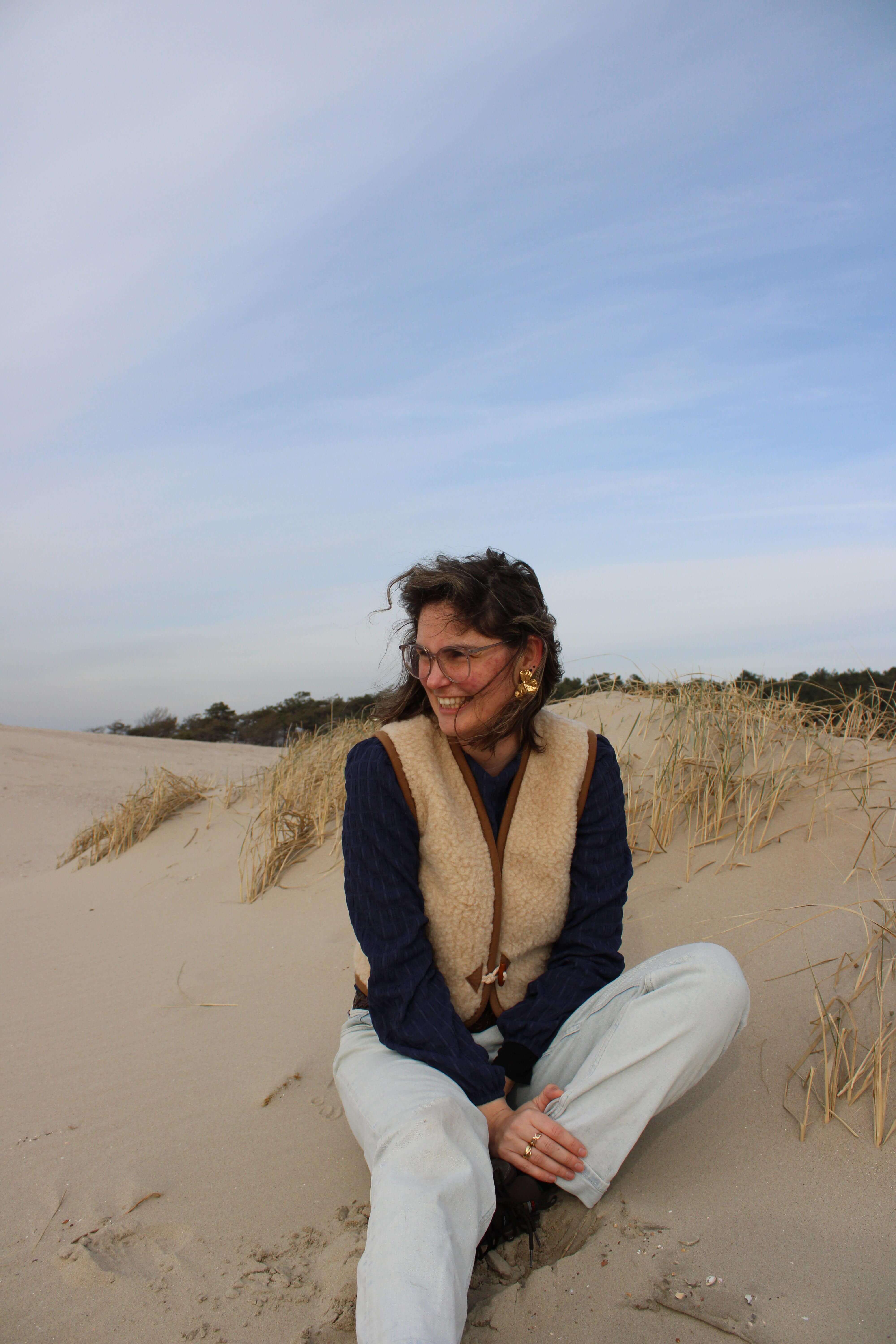 laughing gabrielle sits in sand