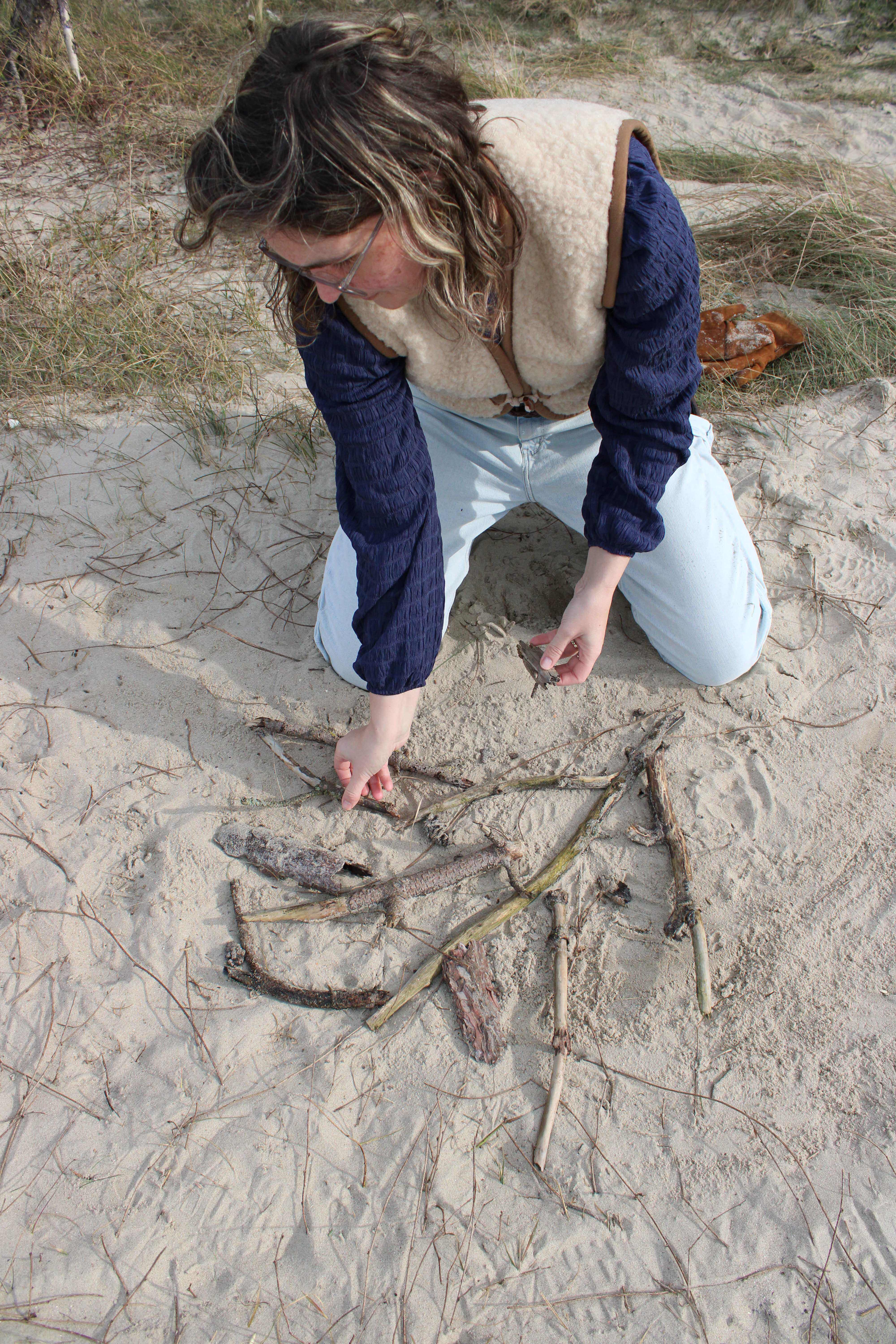 gaby makes a nature artwork sitting in the sand